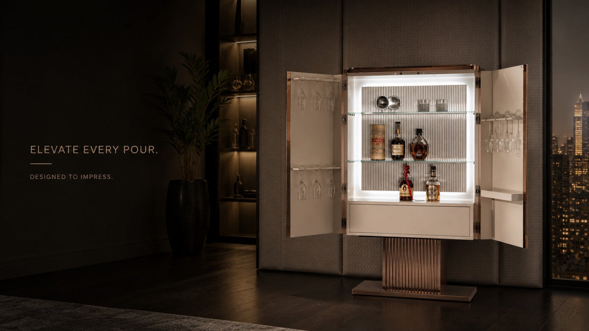 aARGMAC bar cabinet with illuminated glass shelves and rose gold trim, offering bar storage for bottles and glassware, on a fluted pedestal base, set against a lit city skyline view