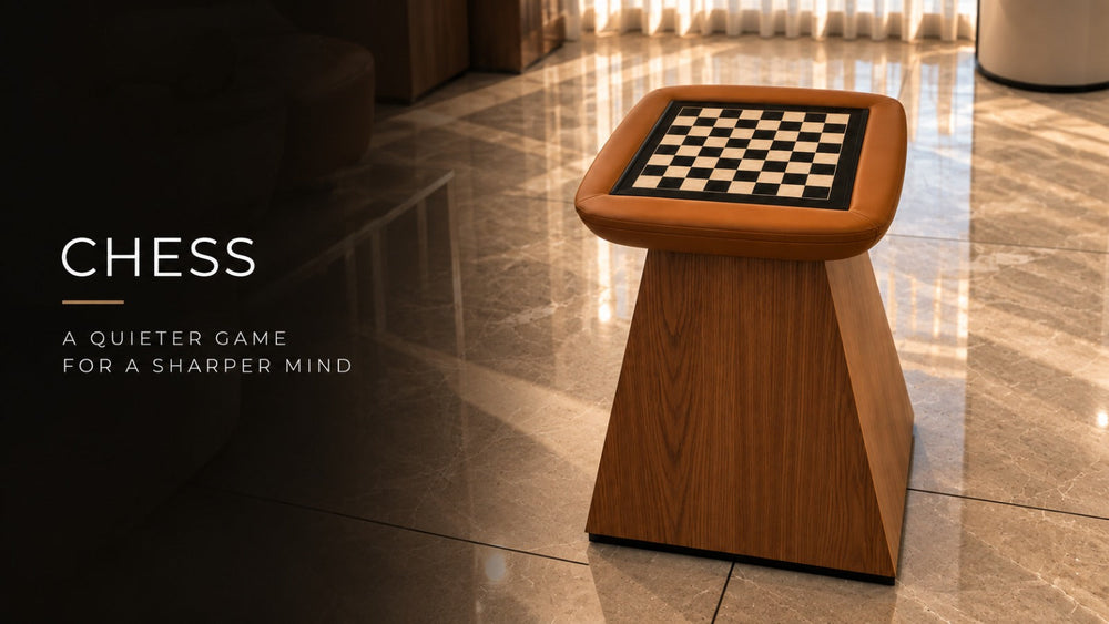 ARGMAC bespoke chess table with a tan leather chess top and inlaid board, raised on an angular wood base, in a sunlit marble-floored lounge.