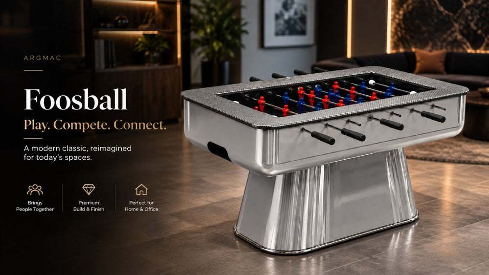 ARGMAC foosball game tables banner featuring a chrome pedestal-base table with red and blue foosball players lined on black rod handles, set in a warm lounge.